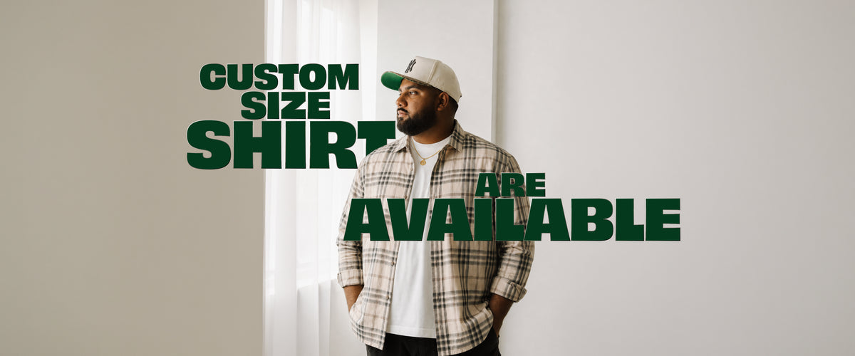 A man wearing a beige and brown plaid flannel shirt over a white t-shirt and a white cap with a green logo, standing against a white wall with large green text overlay that reads 'CUSTOM SIZE SHIRT ARE AVAILABLE'.